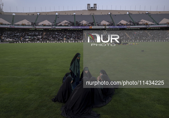 A group of young veiled Iranian schoolgirls are sitting together while participating in a gathering to support mandatory hijab at the Azadi...