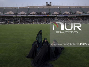 A group of young veiled Iranian schoolgirls are sitting together while participating in a gathering to support mandatory hijab at the Azadi...