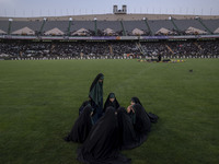 A group of young veiled Iranian schoolgirls are sitting together while participating in a gathering to support mandatory hijab at the Azadi...