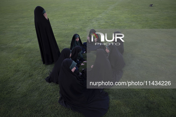 A group of young veiled Iranian schoolgirls are sitting together while participating in a gathering to support mandatory hijab at the Azadi...