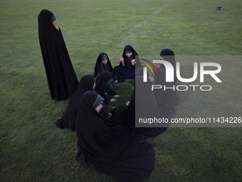 A group of young veiled Iranian schoolgirls are sitting together while participating in a gathering to support mandatory hijab at the Azadi...