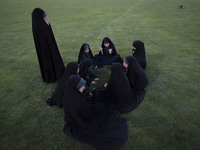 A group of young veiled Iranian schoolgirls are sitting together while participating in a gathering to support mandatory hijab at the Azadi...