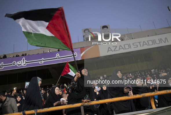 A veiled elderly Iranian woman is waving a Palestinian flag while participating in a family rally to support mandatory hijab, at the Azadi (...