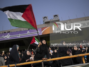 A veiled elderly Iranian woman is waving a Palestinian flag while participating in a family rally to support mandatory hijab, at the Azadi (...