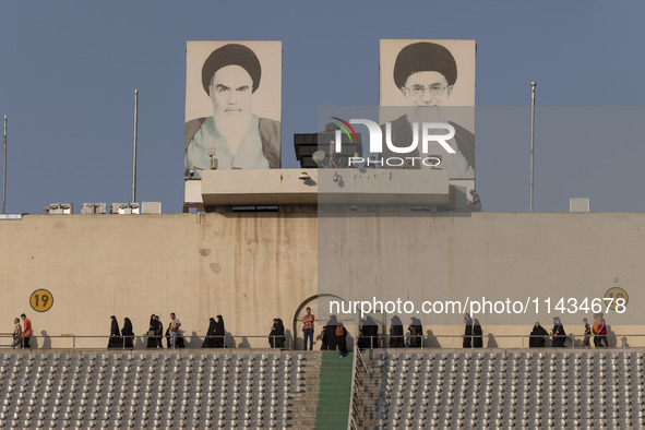 Veiled Iranian women are walking under portraits of Iran's Late Leader, Ayatollah Ruhollah Khomeini (L), and Supreme Leader, Ayatollah Ali K...