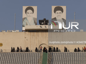 Veiled Iranian women are walking under portraits of Iran's Late Leader, Ayatollah Ruhollah Khomeini (L), and Supreme Leader, Ayatollah Ali K...