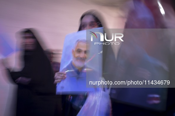 A veiled Iranian woman is carrying a portrait of former commander of the Islamic Revolutionary Guard Corps' (IRGC) Quds Force, Major General...