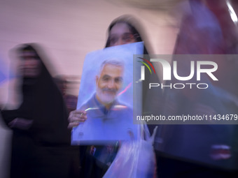 A veiled Iranian woman is carrying a portrait of former commander of the Islamic Revolutionary Guard Corps' (IRGC) Quds Force, Major General...