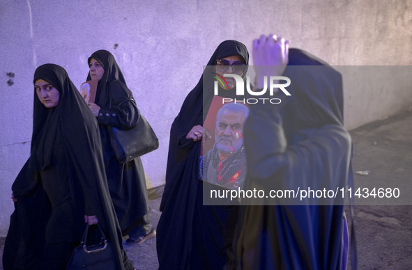 A veiled Iranian woman is carrying a portrait of former commander of the Islamic Revolutionary Guard Corps' (IRGC) Quds Force, Major General...