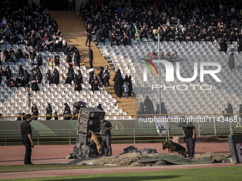 Two security personnel are searching an area with dogs before the beginning of a family rally to support mandatory hijab, at the Azadi (Free...