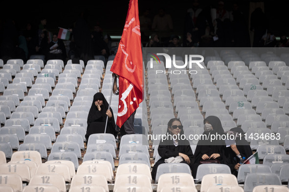 A veiled Iranian woman is holding a religious flag while waiting for the beginning of a family rally to support mandatory hijab, at the Azad...