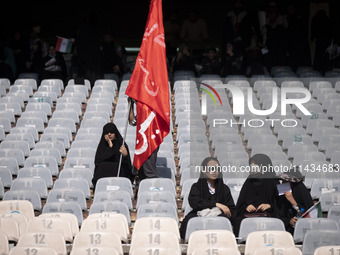 A veiled Iranian woman is holding a religious flag while waiting for the beginning of a family rally to support mandatory hijab, at the Azad...