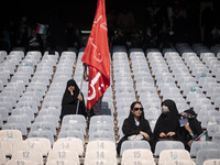 A veiled Iranian woman is holding a religious flag while waiting for the beginning of a family rally to support mandatory hijab, at the Azad...