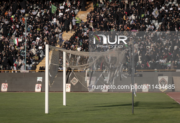 Religious headbands are being tied on a soccer goal, while veiled Iranian women are participating in a family rally to support mandatory hij...