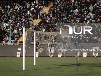 Religious headbands are being tied on a soccer goal, while veiled Iranian women are participating in a family rally to support mandatory hij...