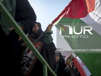 Young veiled women are carrying an Iranian flag and a Palestinian flag while participating in a family rally to support mandatory hijab, in...