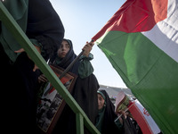 Young veiled women are carrying an Iranian flag and a Palestinian flag while participating in a family rally to support mandatory hijab, in...