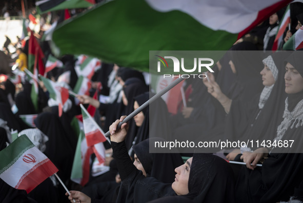 A young veiled Iranian woman is waving a Palestinian flag while participating in a family rally to support mandatory hijab, at the Azadi (Fr...