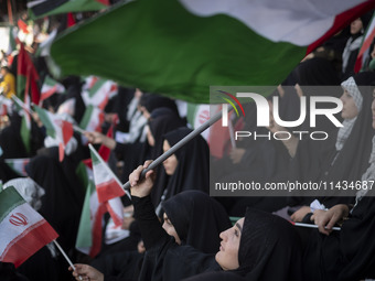 A young veiled Iranian woman is waving a Palestinian flag while participating in a family rally to support mandatory hijab, at the Azadi (Fr...