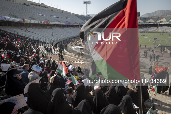 A young veiled Iranian woman (not pictured) is waving a Palestinian flag while participating in a family rally to support mandatory hijab, a...