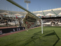 A religious flag and headbands are hanging and tied on a soccer goal, while veiled Iranian women are participating in a family rally to supp...