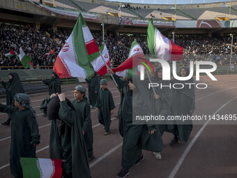 A group of young veiled women is waving Iranian flags while performing in a family rally to support mandatory hijab, at the Azadi (Freedom)...