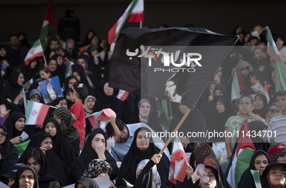 A young veiled Iranian woman is waving a black flag with a Persian script that reads, Daughters of the Revolution, while participating in a...