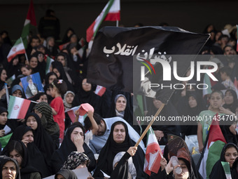 A young veiled Iranian woman is waving a black flag with a Persian script that reads, Daughters of the Revolution, while participating in a...