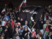 A young veiled Iranian woman is waving a black flag with a Persian script that reads, Daughters of the Revolution, while participating in a...