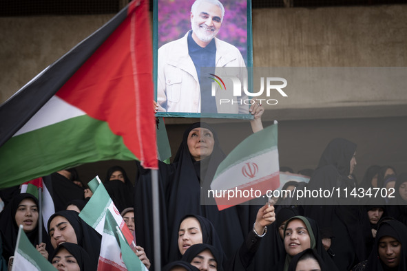 A veiled Iranian woman is holding up a portrait of former commander of the Islamic Revolutionary Guard Corps' (IRGC) Quds Force, Major Gener...