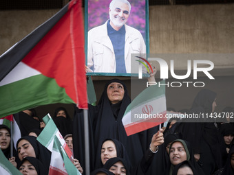 A veiled Iranian woman is holding up a portrait of former commander of the Islamic Revolutionary Guard Corps' (IRGC) Quds Force, Major Gener...