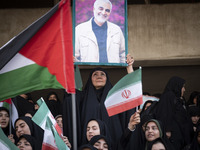 A veiled Iranian woman is holding up a portrait of former commander of the Islamic Revolutionary Guard Corps' (IRGC) Quds Force, Major Gener...