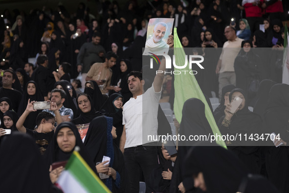 An Iranian man is holding up a portrait of former commander of the Islamic Revolutionary Guard Corps' (IRGC) Quds Force, Major General Qasse...