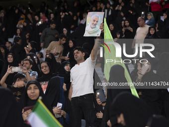 An Iranian man is holding up a portrait of former commander of the Islamic Revolutionary Guard Corps' (IRGC) Quds Force, Major General Qasse...