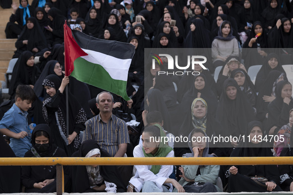 A young Iranian woman (bottom C) is sitting next to veiled women and their families while she is participating in a family rally to support...