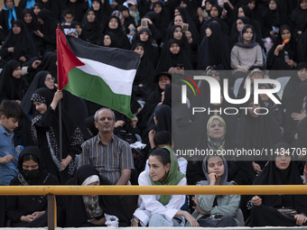 A young Iranian woman (bottom C) is sitting next to veiled women and their families while she is participating in a family rally to support...