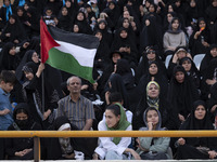 A young Iranian woman (bottom C) is sitting next to veiled women and their families while she is participating in a family rally to support...