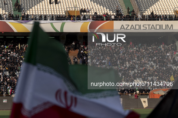 An Iranian flag is waving while veiled women and their families are participating in a family rally to support mandatory hijab, at the Azadi...