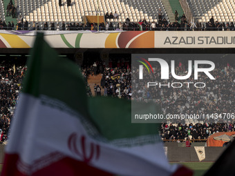 An Iranian flag is waving while veiled women and their families are participating in a family rally to support mandatory hijab, at the Azadi...