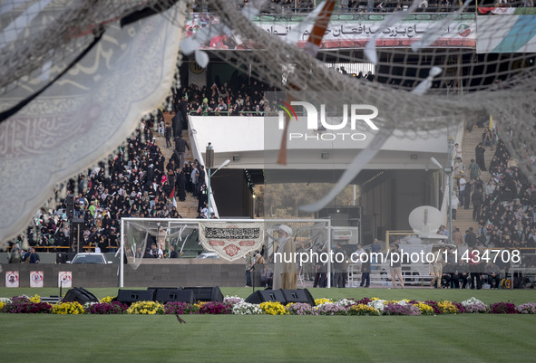 A religious flag and headbands are hanging and tied on soccer goals, while a cleric is delivering speeches, during a family rally to support...