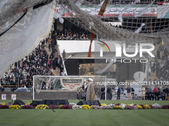 A religious flag and headbands are hanging and tied on soccer goals, while a cleric is delivering speeches, during a family rally to support...