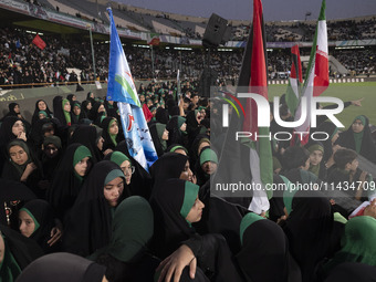 Young veiled women are carrying Iranian and Palestinian flags while they are participating in a family rally to support mandatory hijab at t...