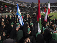 Young veiled women are carrying Iranian and Palestinian flags while they are participating in a family rally to support mandatory hijab at t...