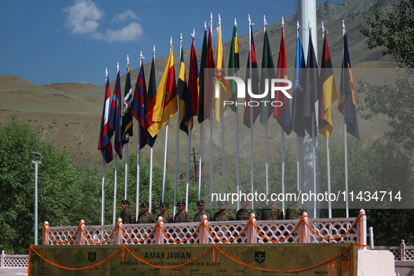 Indian army personnel are standing under regimental flags at a war memorial during the ''Vijay Diwas'' or Victory Day celebration in Drass,...