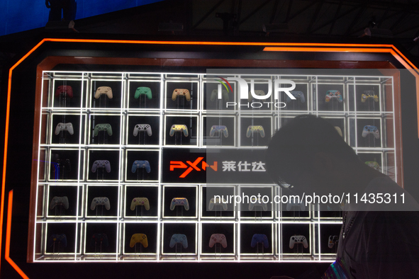 A man is standing in front of PXN games controllers at the PXN booth during the Chinajoy games fair in Shanghai, China, on July 26, 2024. 