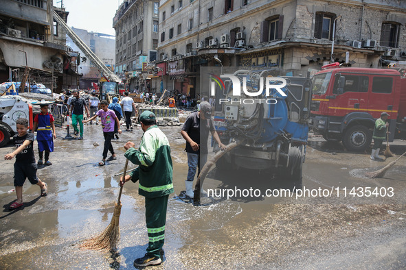 Workers are cleaning up the streets after the firefighters of the Civil Defense are controlling a huge fire that broke out in several stores...