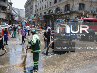 Workers are cleaning up the streets after the firefighters of the Civil Defense are controlling a huge fire that broke out in several stores...