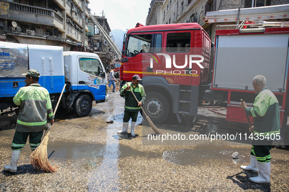 Workers are cleaning up the streets after the firefighters of the Civil Defense are controlling a huge fire that broke out in several stores...