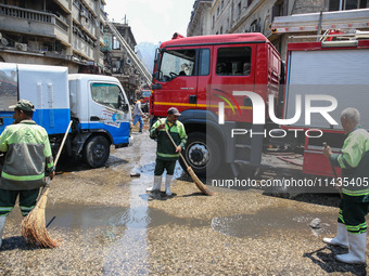 Workers are cleaning up the streets after the firefighters of the Civil Defense are controlling a huge fire that broke out in several stores...