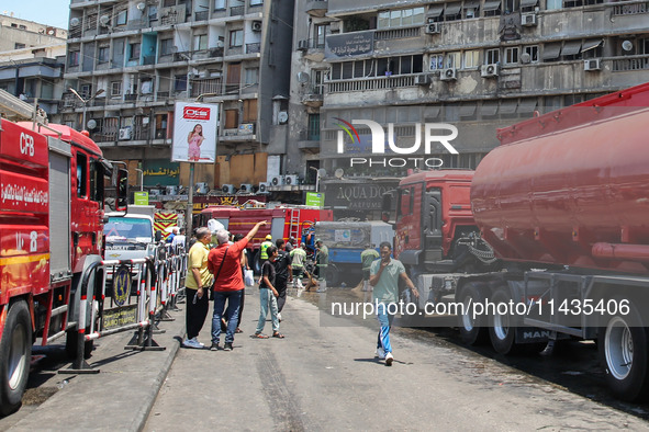 Pedestrians are in the street after the firefighters of the Civil Defense are controlling a huge fire that broke out in several stores, in M...